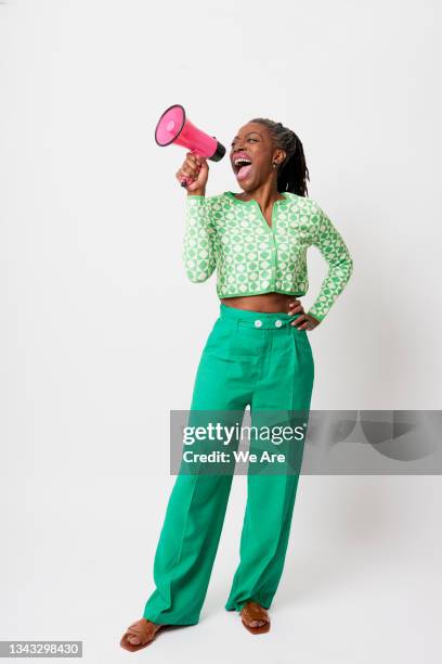 full length portrait of mature woman shouting a message through a  megaphone - megaphone fotografías e imágenes de stock