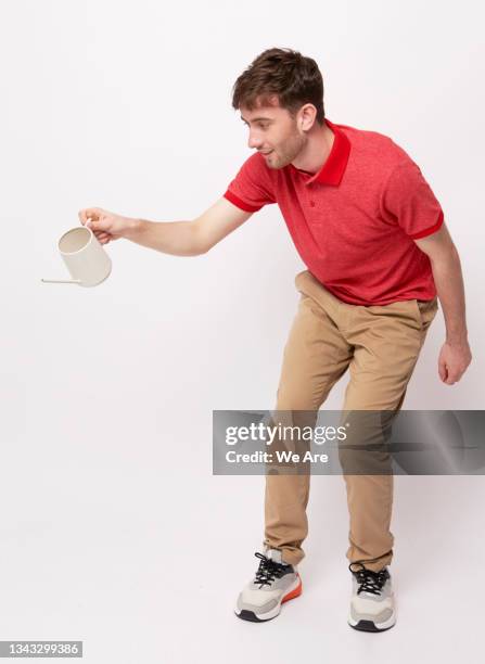 young man using watering can - khakibyxor bildbanksfoton och bilder