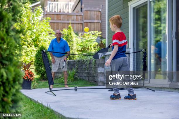 grandfather and grandson playing pickleball at home in summer - senior tennis stock pictures, royalty-free photos & images