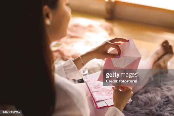 young woman opening a love letter - love letter stock pictures, royalty-free photos & images