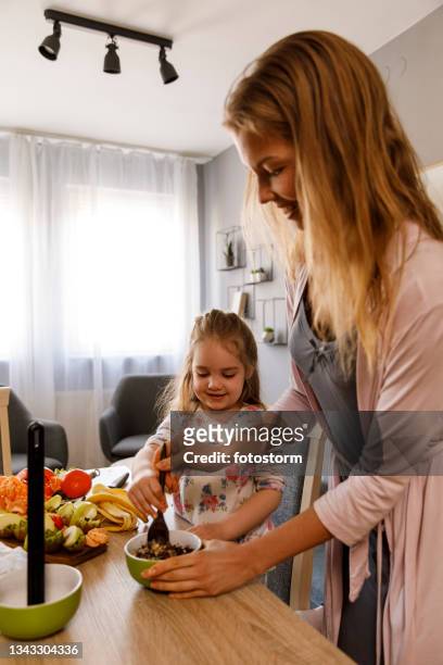 little girl assisting her mother in preparing a healthy snack - chocolate pudding imagens e fotografias de stock