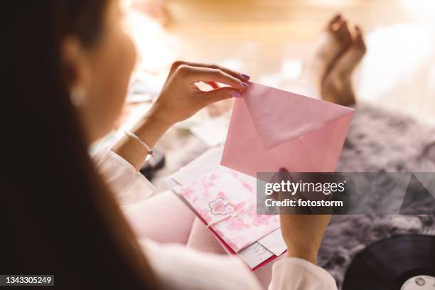 jovem abrindo um envelope rosa com uma carta de amor - thinking of you card - fotografias e filmes do acervo