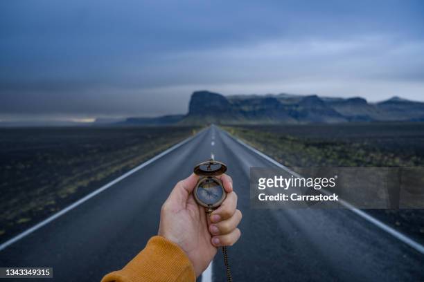 compass in hand background of mountain road in iceland with a glacier in the background - navigational compass stockfoto's en -beelden