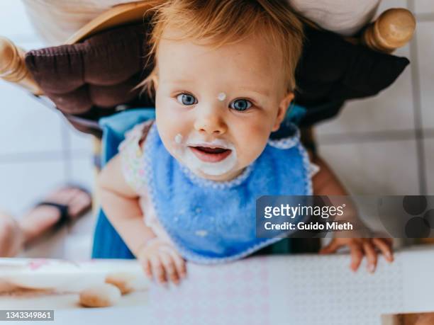 happy baby girl looking up after eating joghurt. - baby eating yogurt stockfoto's en -beelden