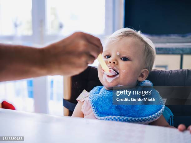 happy baby girl eating joghurt. - baby eating yogurt stockfoto's en -beelden