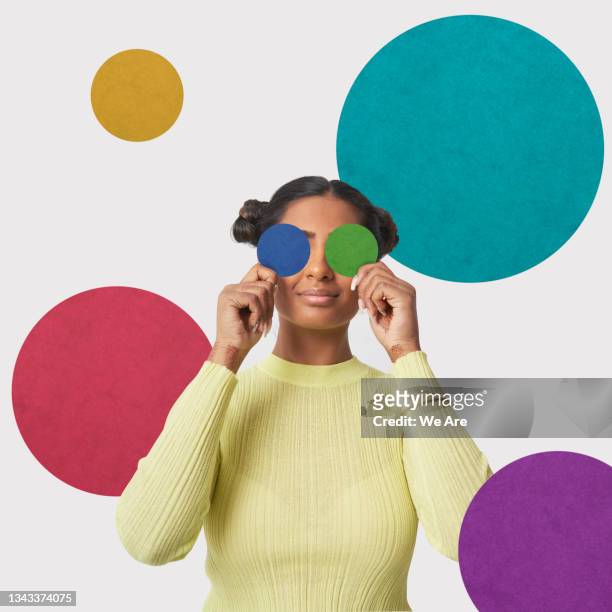 young woman holding colourful dots over her eyes - bloco de cor imagens e fotografias de stock