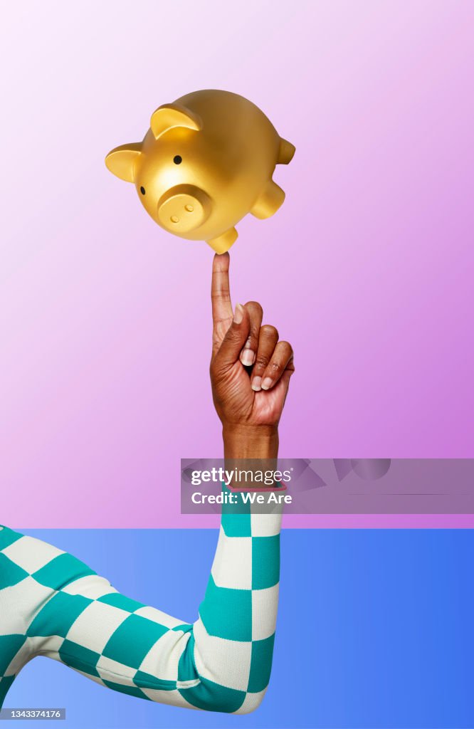 Piggy bank balancing on finger