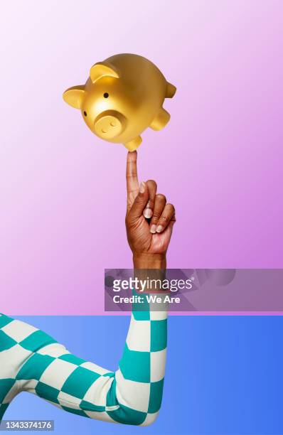 piggy bank balancing on finger - money fotografías e imágenes de stock