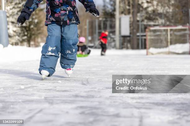 kids ice-skating on ice rink outdoors in winter - learning to ice skate stock pictures, royalty-free photos & images