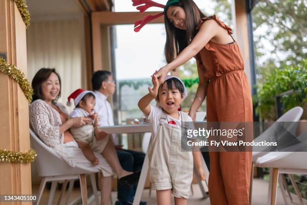 loving mother dancing with son while celebrating christmas at home with family - winter australia stockfoto's en -beelden