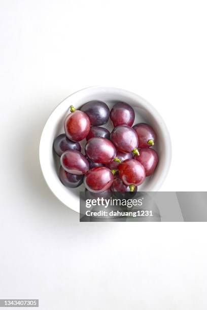 fresh purple grapes in a white porcelain bowl on a white background - red grapes imagens e fotografias de stock