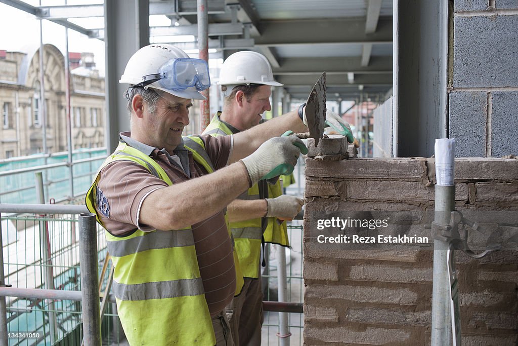 Bricklayesrs work on building wall