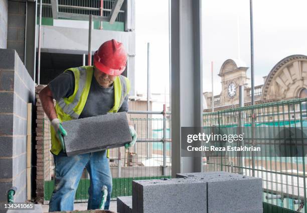 construction worker moves cinder block on site - trabalhador manual imagens e fotografias de stock