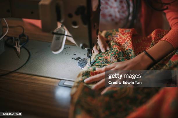 close up top view high angle asian chinese teenage girl's hand holding batik sewing stitching on sewing machine illuminated by led light - malaysia batik stock pictures, royalty-free photos & images
