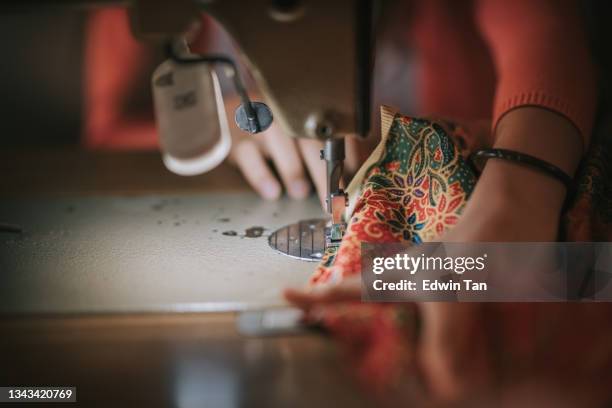 nahaufnahme draufansicht hochwinkel asiatisches chinesisches teenager-mädchen hand halten batik nähenähten auf nähmaschine beleuchtet durch led-licht beleuchtet - saum muster stock-fotos und bilder