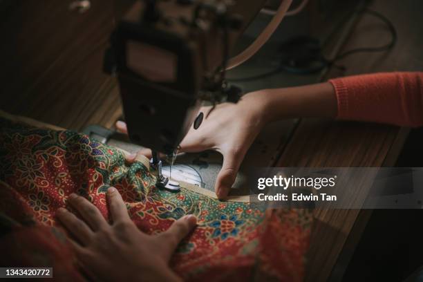 nahaufnahme draufansicht hochwinkel asiatisches chinesisches teenager-mädchen hand halten batik nähenähten auf nähmaschine beleuchtet durch led-licht beleuchtet - textile factory stock-fotos und bilder