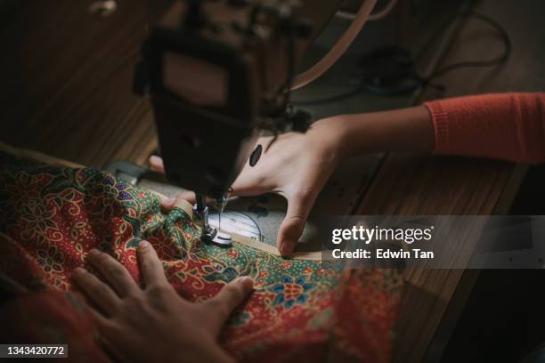 close up top view high angle asian chinese teenage girl's hand holding batik sewing stitching on sewing machine illuminated by led light - pin up girl stockfoto's en -beelden