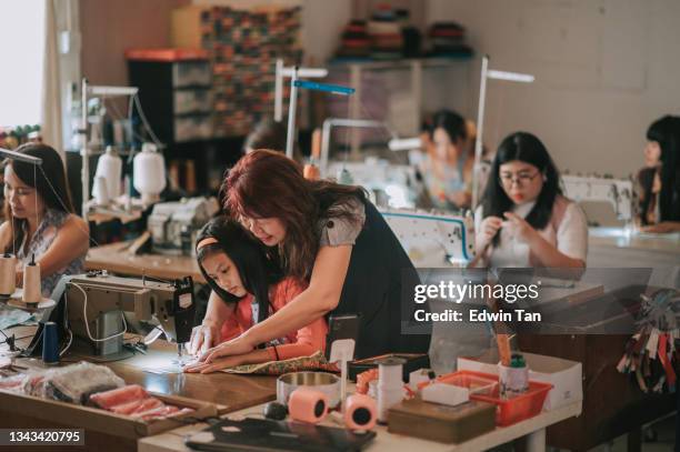 asian chinese mature woman tailor teaching her sewing class student on sewing skill with sewing machine at her studio - asian pin up girls stockfoto's en -beelden
