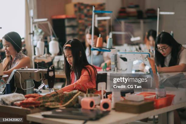 asian chinese young girl and woman student participating in sewing class during weekend using sewing machine - textielfabriek stockfoto's en -beelden