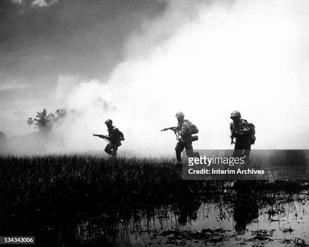 View of crack troops of the Vietnamese Army running across marshy terrain in Vietnam's delta country, during operations against the Communist Viet...