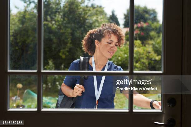female nurse ringing doorbell - arriving home stockfoto's en -beelden