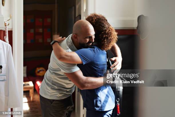 smiling man embracing female medical worker - pflegedienst blau stock-fotos und bilder