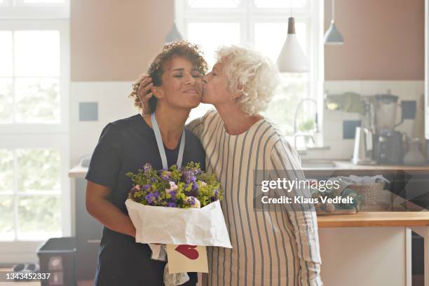 senior woman kissing nurse at home - elderly receiving paperwork stock pictures, royalty-free photos & images