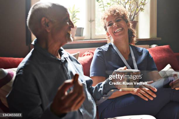 cheerful female nurse talking with senior man - tea cup stock pictures, royalty-free photos & images