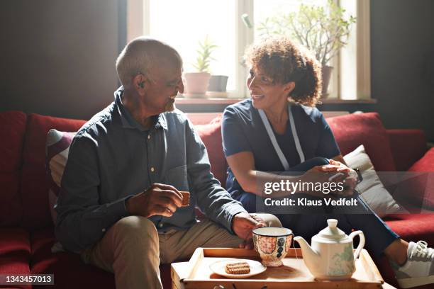 caregiver talking with man having biscuit and tea - man tray food holding stockfoto's en -beelden