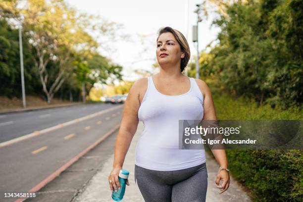 woman walking in the city park - mid adult women stock pictures, royalty-free photos & images