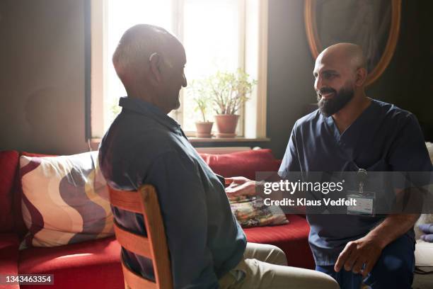 male nurse talking with senior man - nurse with old male patient home care stock-fotos und bilder