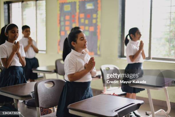 school children saying their prayer in the classroom - child praying school stock pictures, royalty-free photos & images