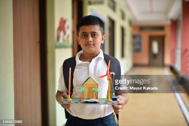 school boy carrying his science project solar panel and windmill project - schoolboy stock pictures, royalty-free photos & images