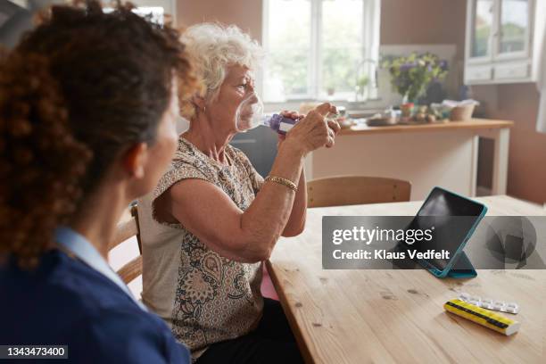 senior woman pumping inhaler at home - nebulizador fotografías e imágenes de stock