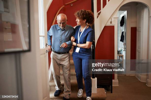 nurse walking with senior man on steps - medical assistance fotografías e imágenes de stock