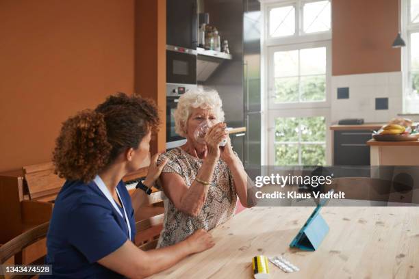 senior woman inhaling by female nurse - nebulizador fotografías e imágenes de stock