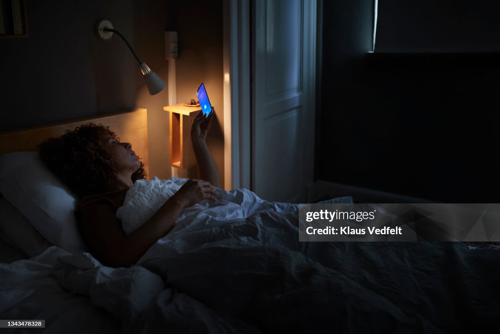 Woman waking up through alarm ring on smart phone