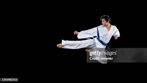 joueur de karaté masculin effectuant un coup de pied volant - ceinture bleue photos et images de collection