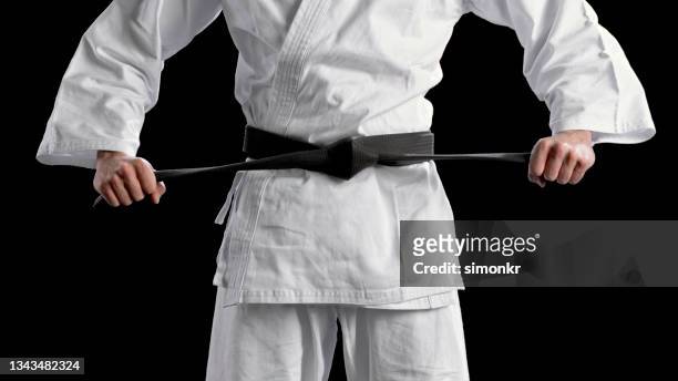male karate player standing against black background - vechtkunst stockfoto's en -beelden