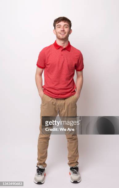 portrait of young man standing with hands in his pockets - khaki tan fotografías e imágenes de stock