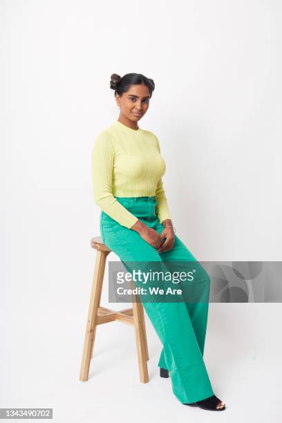 portrait of young fashionable woman sitting on stool - stool imagens e fotografias de stock