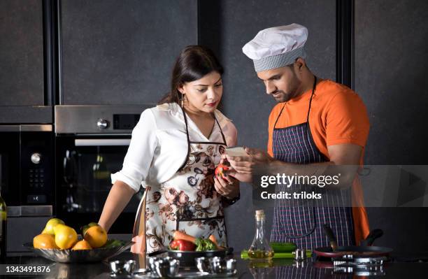 paar schaut sich video an, während es vegane mahlzeit zubereitet - lady cooking confused stock-fotos und bilder