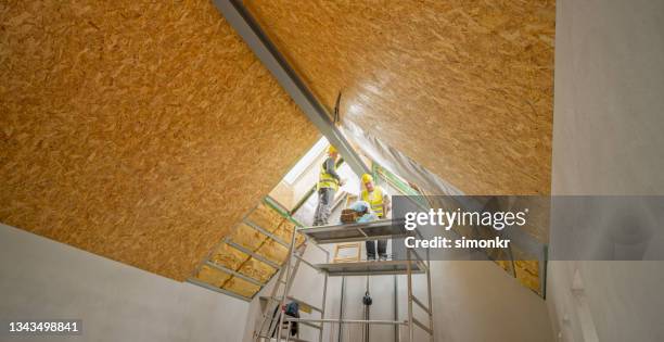 trabajadores de la construcción trabajando en el andamio debajo del techo - aislante fotografías e imágenes de stock