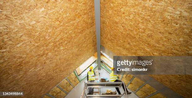 construction workers working on the scaffold below the ceiling - house insulation not posing stock pictures, royalty-free photos & images