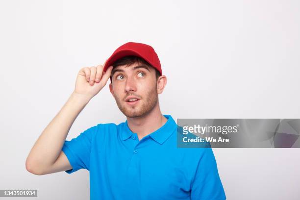 young man holding brim of red cap - man cap stock pictures, royalty-free photos & images
