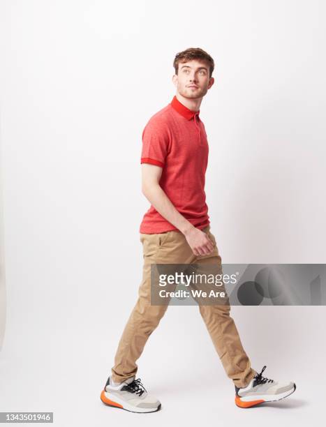 young man walking through a space in a carefree way - full body isolated stockfoto's en -beelden