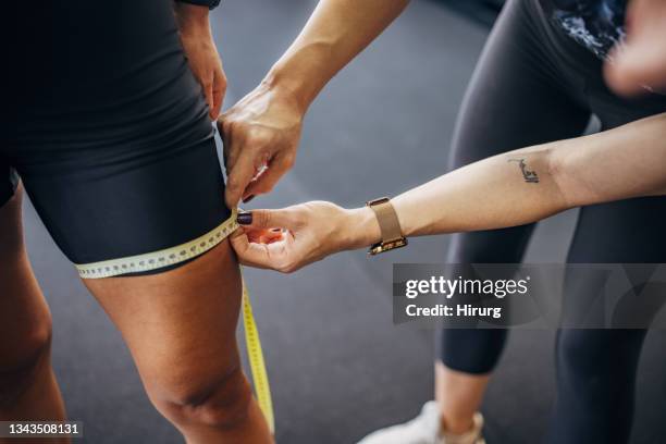 femme en forme mesurant sa cuisse - thigh stock photos et images de collection