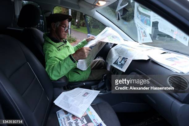 Johann Böhm reads newspapers during a break as he deliver newspapers to residents on the day after German federal parliamentary elections on...