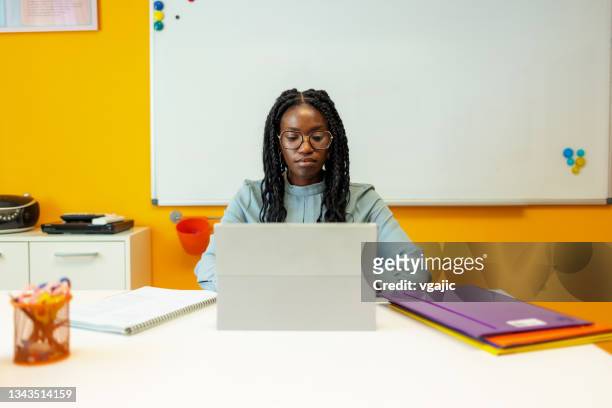 insegnante nera seduta alla sua scrivania in classe - teacher desk foto e immagini stock
