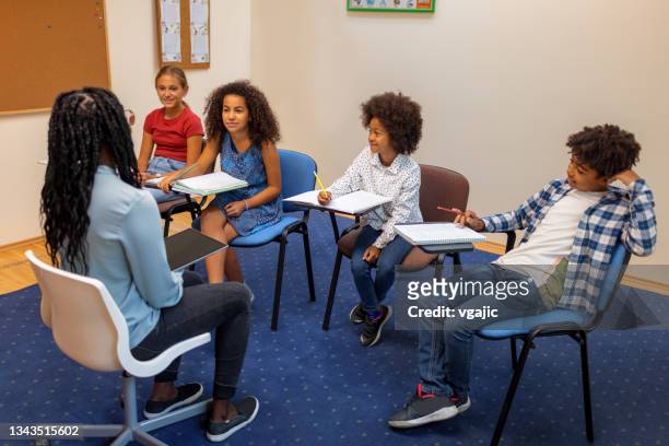 female teacher talks with small group of students - small group of people stock pictures, royalty-free photos & images